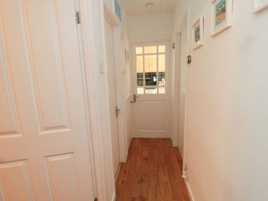A hallway with wooden floor and white doors including a glass panel door at Barnacles in Boulmer near Longhoughton