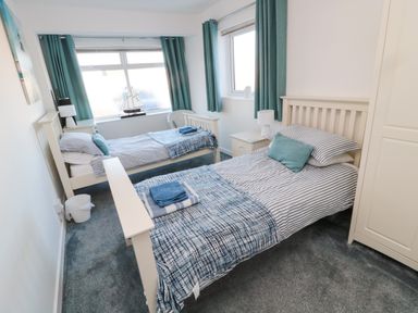A bedroom with two single beds small bedside tables and a wardrobe at Barnacles Boulmer near Longhoughton
