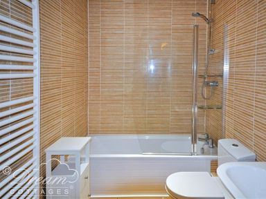 A bathroom with a bathtub shower combination toilet sink cabinet and towel radiator at Admirals Quarter Apartment 5 Weymouth