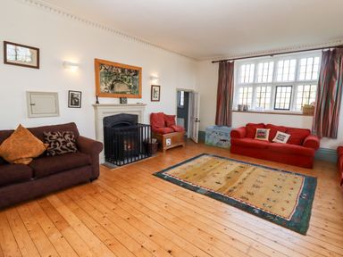 A living room with sofas a fireplace a rug and a large window at Wick Court Farm Arlingham near Frampton On Severn