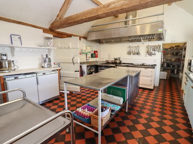 A kitchen with stainless steel tables and cooking utensils hanging on the wall at Wick Court Farm in Arlingham near Frampton On Severn