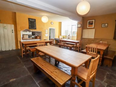 A dining room with wooden tables and chairs and yellow walls at Wick Court Farm Arlingham near Frampton On Severn
