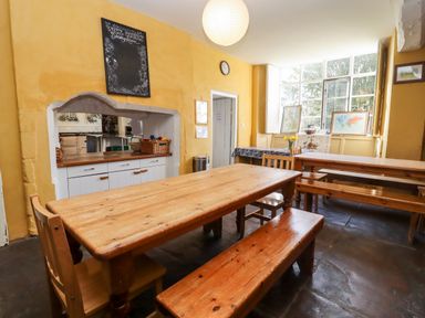 A dining room with wooden tables and benches a chalkboard and maps on a windowsill at Wick Court Farm Arlingham near Frampton On Severn