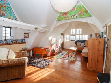 A reading room with wicker armchair bookshelves and a sofa at Wick Court Farm in Arlingham near Frampton On Severn