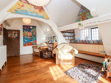 A reading room with armchairs bookshelves and colorful artwork at Wick Court Farm in Arlingham near Frampton On Severn