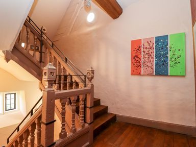 A staircase with wooden railings and a colorful painting on the wall at Wick Court Farm in Arlingham near Frampton On Severn