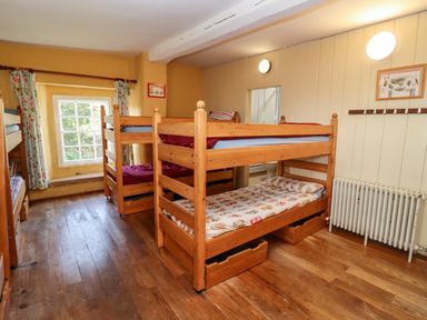 A bedroom with bunk beds wooden floor a window with floral curtains and a radiator at Wick Court Farm Arlingham near Frampton On Severn
