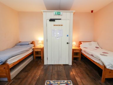 A bedroom with two single beds and wooden floors at Wick Court Farm in Arlingham near Frampton On Severn