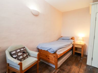 A bedroom with a single bed chair with a sheep cushion and a wooden bedside table with a lamp at Wick Court Farm in Arlingham near Frampton On Severn