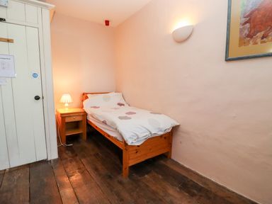A small bedroom with single wooden bed bedside table lamp and wooden floor at Wick Court Farm in Arlingham near Frampton On Severn