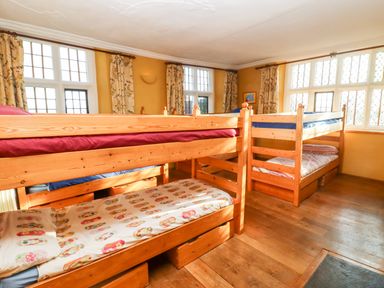 A bedroom with wooden bunk beds and patterned curtains at Wick Court Farm Arlingham near Frampton On Severn