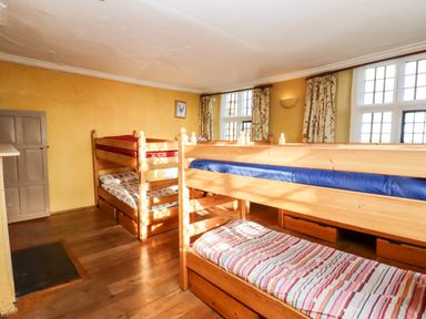 A bedroom with two wooden bunk beds under windows with patterned curtains at Wick Court Farm Arlingham near Frampton On Severn
