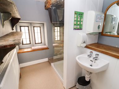 A bathroom with a small sink mirror soap dispenser hand washing instructions and a shower at Wick Court Farm Arlingham near Frampton On Severn