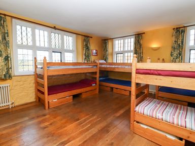 A bedroom with four wooden bunk beds and large windows at Wick Court Farm in Arlingham near Frampton On Severn