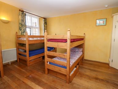 A bedroom with two wooden bunk beds a window with curtains and wooden floor at Wick Court Farm Arlingham near Frampton On Severn
