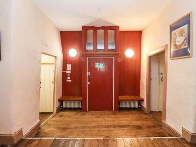 A hallway with wooden floor two side doors and a red fire exit door at Wick Court Farm in Arlingham near Frampton On Severn