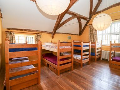 A dormitory room with wooden bunk beds and large windows at Wick Court Farm in Arlingham near Frampton On Severn