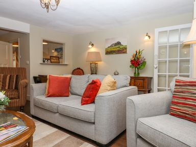 A living room with grey sofas and a striped armchair at Early Mist Cottage in Haytor Vale