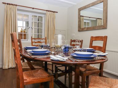 A dining room with wooden table set with blue and white dishes and wooden chairs at Early Mist Cottage in Haytor Vale