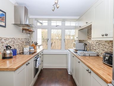 A kitchen with wooden countertops white cabinets and appliances at Early Mist Cottage in Haytor Vale