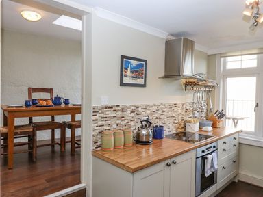 A kitchen with wooden countertop and stove next to a dining area with wooden table and chairs at Early Mist Cottage in Haytor Vale