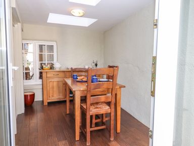 A dining area with a wooden table and chairs and a sideboard under a skylight at Early Mist Cottage in Haytor Vale