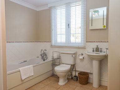 A bathroom with a bathtub toilet sink and window with blinds at Early Mist Cottage in Haytor Vale