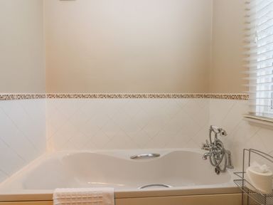 A bathroom with a bathtub tiled walls and a towel hanging on the tub at Early Mist Cottage in Haytor Vale