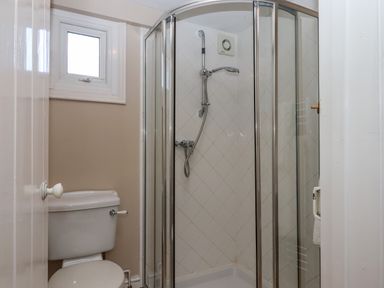 A bathroom with a toilet and a corner shower enclosure with glass doors at Early Mist Cottage in Haytor Vale