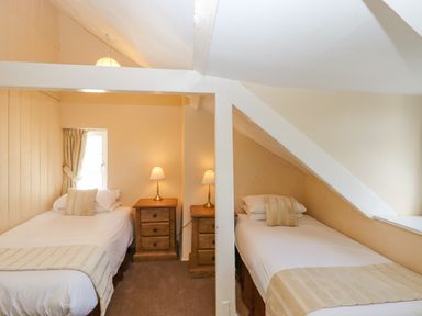 A attic bedroom with two single beds and wooden bedside tables at Early Mist Cottage in Haytor Vale