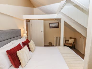 A bedroom with a bed and multiple pillows a chair radiator and a framed picture at Early Mist Cottage in Haytor Vale