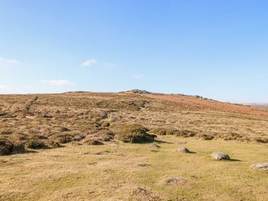 A moorland landscape with grass and rocks under a clear blue sky at Early Mist Cottage in Haytor Vale
