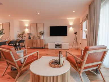 A living room with two leather armchairs and a round coffee table with a candle and woven basket at 7 Longshore in St Columb Minor