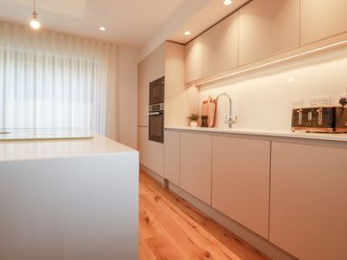 A kitchen with cabinets a sink a toaster and wooden flooring at 7 Longshore in St Columb Minor