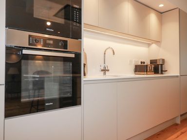 A kitchen with built in oven and microwave a sink with a faucet and a toaster on a white countertop at 7 Longshore in St Columb Minor