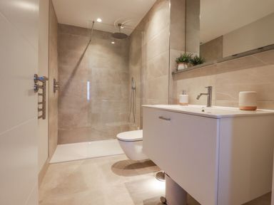 A bathroom with a walk-in shower a wall-mounted toilet and a white vanity unit with sink at 7 Longshore in St Columb Minor