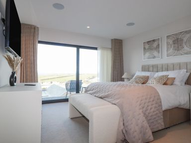 A bedroom with a bed bench and dresser with a vase in 7 Longshore in St Columb Minor