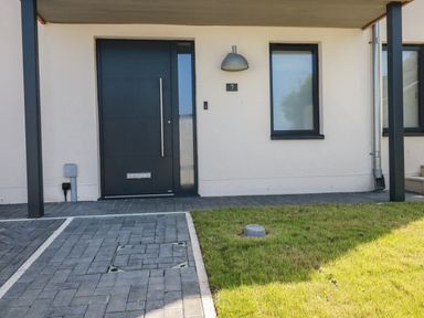A front entrance with a dark door a window a light fixture and a grass lawn at 7 Longshore in St Columb Minor