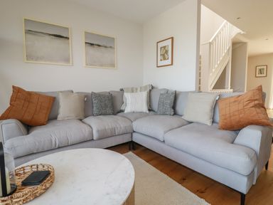 A corner sofa with cushions and framed pictures on the walls in a living room at 7 Longshore in St Columb Minor
