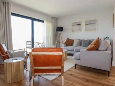A living room with leather chairs a gray sofa wooden side tables and floor lamp at 7 Longshore in St Columb Minor