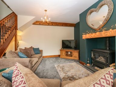 A living room with sofas a television and a wood burning stove at The Anvil in Broughton-In-Furness