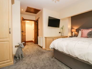 A bedroom with a bed pillows a wall mounted tv wooden cupboards and a dog sculpture at The Anvil in Broughton-In-Furness