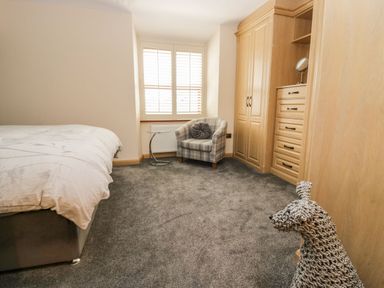 A bedroom with a bed chair small table built in wardrobes and a woven dog figure at The Anvil in Broughton-In-Furness