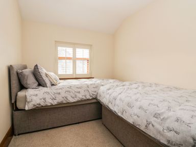 A bedroom with two gray beds under a window with shutters at The Anvil in Broughton-In-Furness