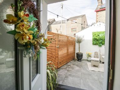 A patio area with wooden fence potted plants and outdoor seating at The Anvil in Broughton-In-Furness