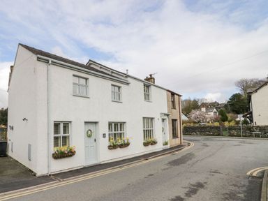 A white house with flower boxes under the windows on a curved road at The Anvil in Broughton-In-Furness