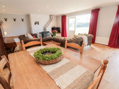 A living room with wooden dining table and chairs with a green wreath on the table at Whiteadder Bank in Berwick-Upon-Tweed
