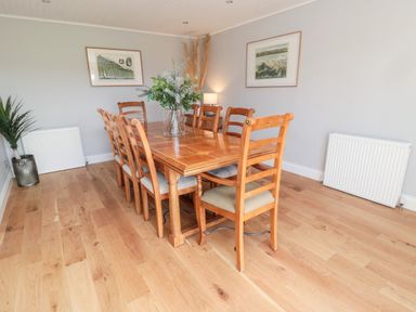 A dining room with a wooden table and six chairs a plant in the corner and framed pictures on the walls at Whiteadder Bank in Berwick-Upon-Tweed