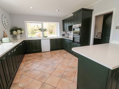 A kitchen with green cabinets white countertops a large window and tiled floor at Whiteadder Bank in Berwick-Upon-Tweed