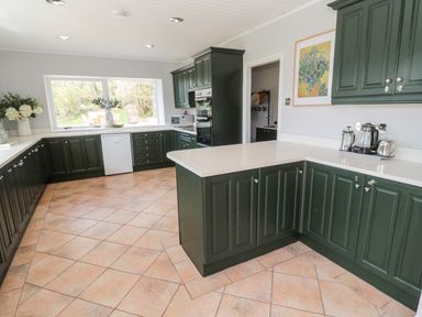 A kitchen with green cabinets white countertops and tiled floor at Whiteadder Bank in Berwick-Upon-Tweed